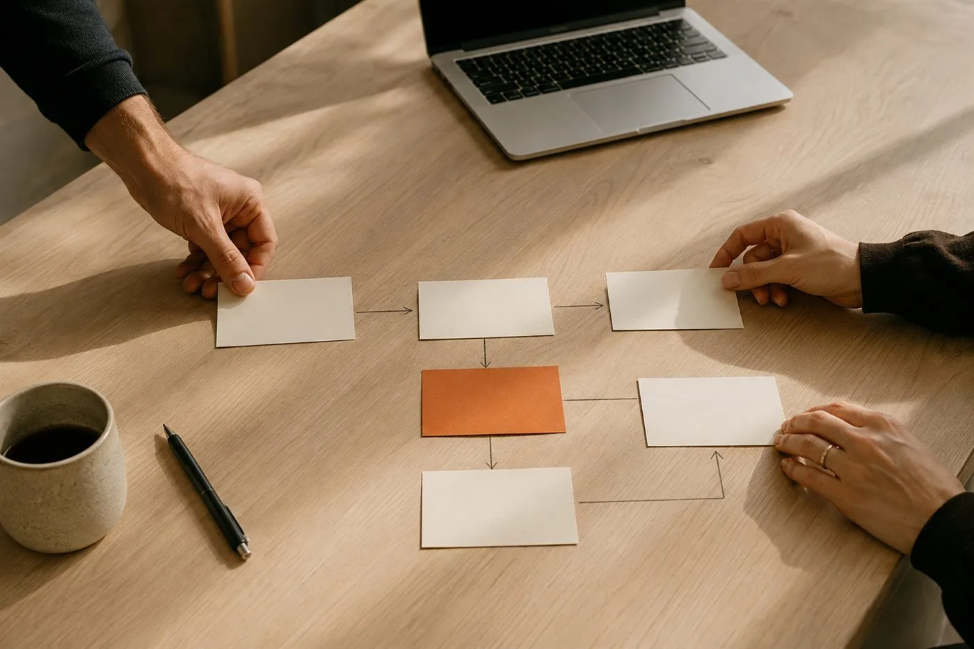 Hands arranging workflow cards on a desk