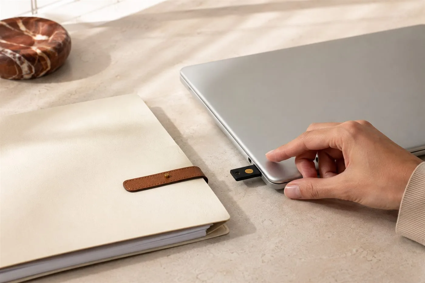 A hardware security key beside a document folder and laptop